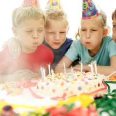 Two Boys and a Girl (8-12) Blowing Out Candles on a Birthday Cake